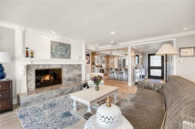 living room with a fireplace, recessed lighting, ornamental molding, wood finished floors, and baseboards