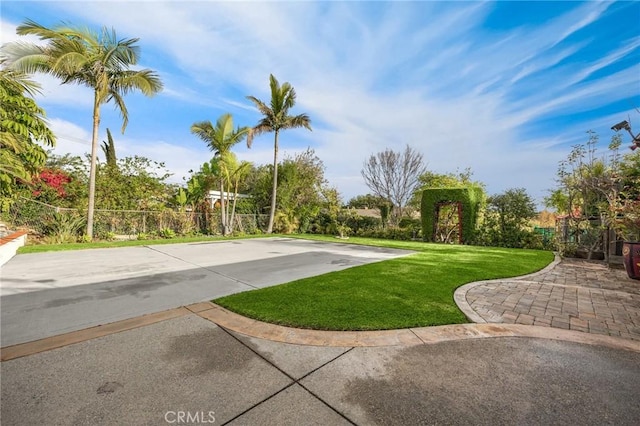 view of property's community with a yard, driveway, and fence