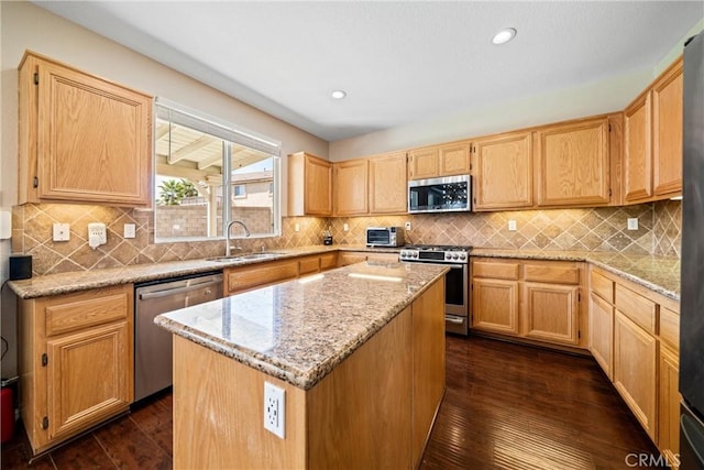 kitchen with dark wood-type flooring, light stone countertops, stainless steel appliances, light brown cabinetry, and a sink