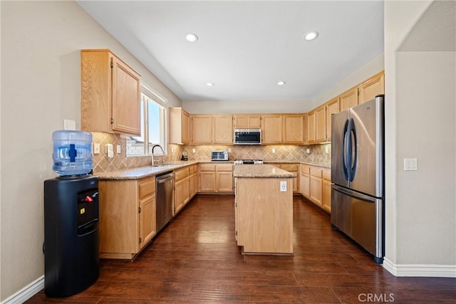 kitchen with dark wood finished floors, light brown cabinetry, appliances with stainless steel finishes, a kitchen island, and a sink