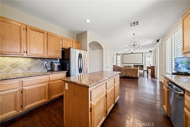 kitchen with arched walkways, stainless steel appliances, dark wood-style flooring, visible vents, and decorative backsplash