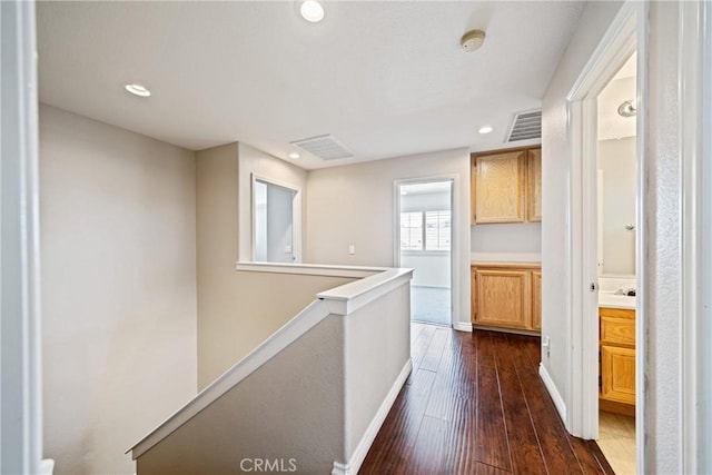 hallway with visible vents, dark wood-style flooring, an upstairs landing, and recessed lighting