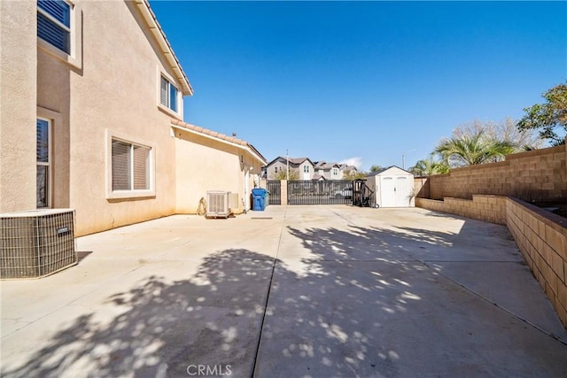 view of patio / terrace featuring an outbuilding, central AC, a storage unit, and a fenced backyard