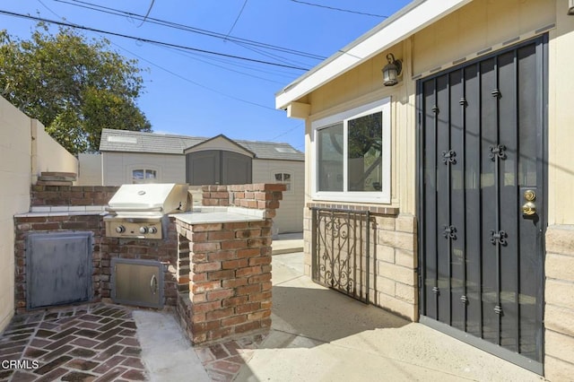 view of patio / terrace featuring fence, a shed, exterior kitchen, an outbuilding, and a grill