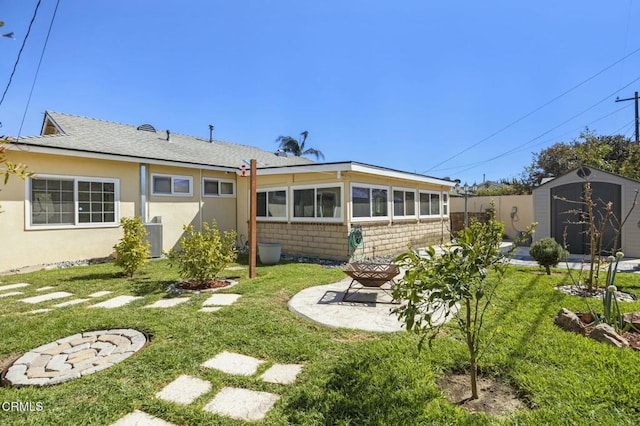 back of house featuring an outbuilding, a storage shed, a lawn, and a patio area