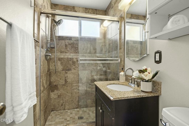 full bathroom featuring a shower stall, vanity, and toilet