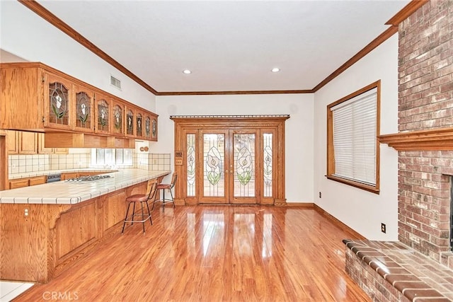 kitchen featuring visible vents, light wood-style floors, french doors, backsplash, and tile counters