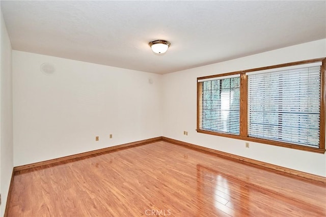 empty room featuring light wood-type flooring and baseboards