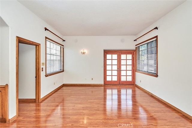 unfurnished room featuring baseboards, french doors, plenty of natural light, and light wood-style floors