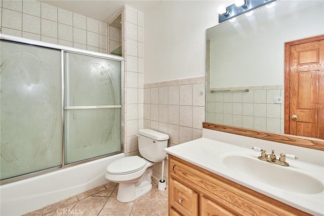 bathroom with enclosed tub / shower combo, tile patterned flooring, toilet, vanity, and tile walls