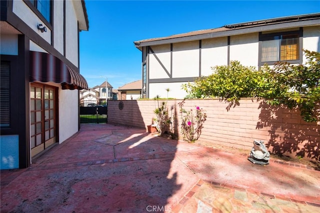 exterior space featuring a gate, fence, a patio, and stucco siding