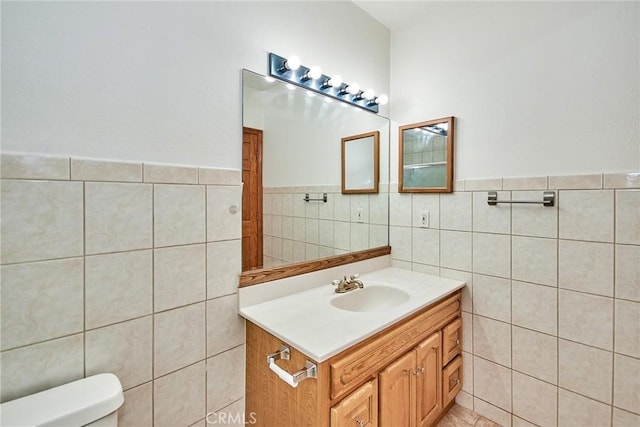 bathroom featuring toilet, tile walls, and vanity