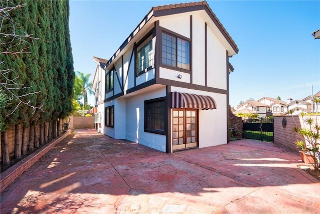 rear view of house featuring a gate, a patio area, fence, and stucco siding