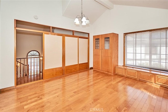 unfurnished bedroom featuring light wood-type flooring, high vaulted ceiling, a chandelier, and beam ceiling