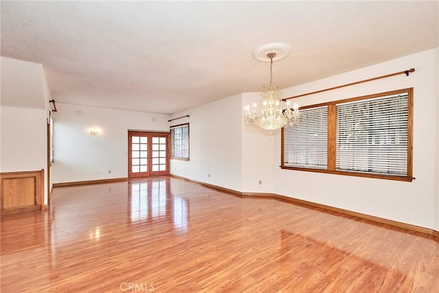 unfurnished room featuring french doors, light wood finished floors, and baseboards