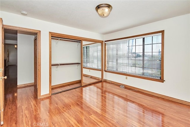 unfurnished bedroom with a closet, wood finished floors, and baseboards