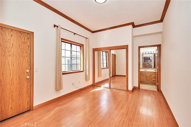 unfurnished bedroom featuring light wood-style floors, baseboards, ornamental molding, and ensuite bathroom