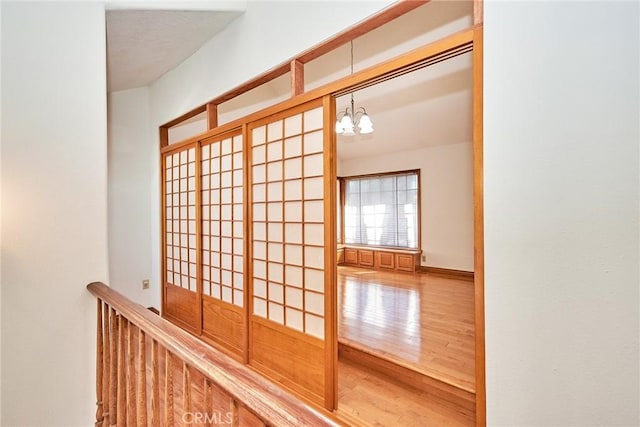 hallway with a chandelier, baseboards, and wood finished floors