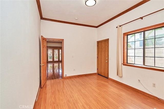 unfurnished room featuring light wood finished floors, baseboards, and ornamental molding