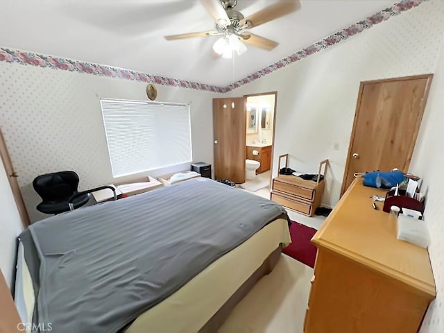 bedroom featuring wallpapered walls, ensuite bath, vaulted ceiling, and a ceiling fan