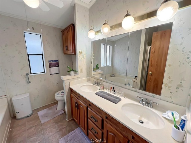 full bathroom with double vanity, a sink, toilet, and wallpapered walls