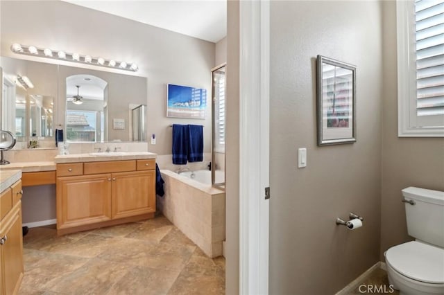 full bath featuring toilet, vanity, a ceiling fan, a shower, and tiled tub