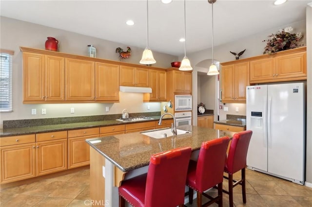 kitchen with a kitchen island with sink, recessed lighting, under cabinet range hood, white appliances, and a sink