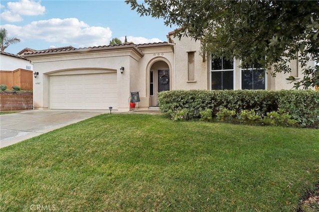 mediterranean / spanish house with an attached garage, a tile roof, concrete driveway, stucco siding, and a front yard