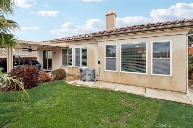 rear view of house featuring a yard, a chimney, cooling unit, and stucco siding