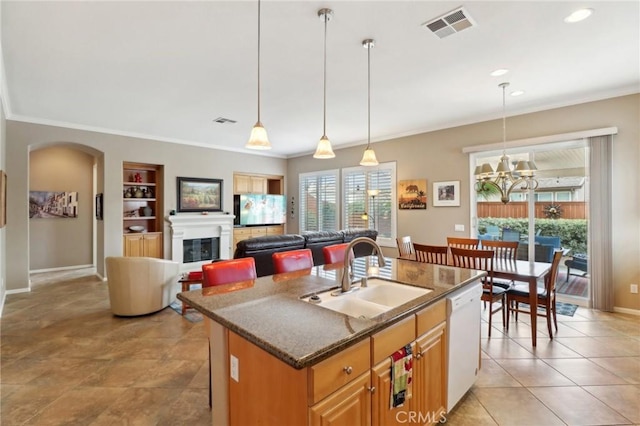 kitchen with visible vents, arched walkways, white dishwasher, built in shelves, and a sink