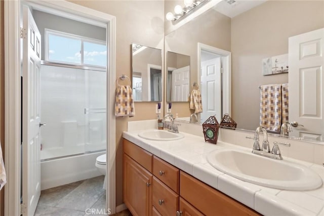 bathroom with double vanity, tile patterned flooring, a sink, and toilet