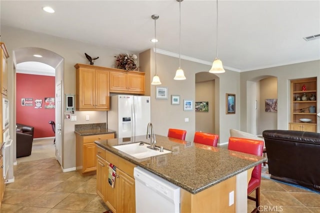 kitchen with white appliances, visible vents, arched walkways, a kitchen bar, and a sink