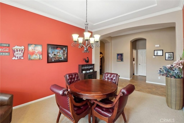 carpeted dining area featuring arched walkways, ornamental molding, an inviting chandelier, and baseboards