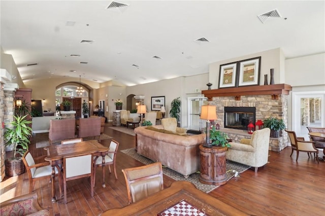 living room with vaulted ceiling, visible vents, a fireplace, and hardwood / wood-style flooring