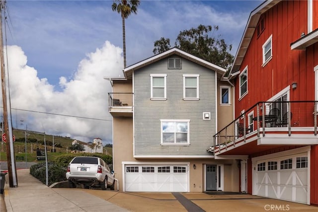 exterior space featuring concrete driveway, a balcony, and an attached garage