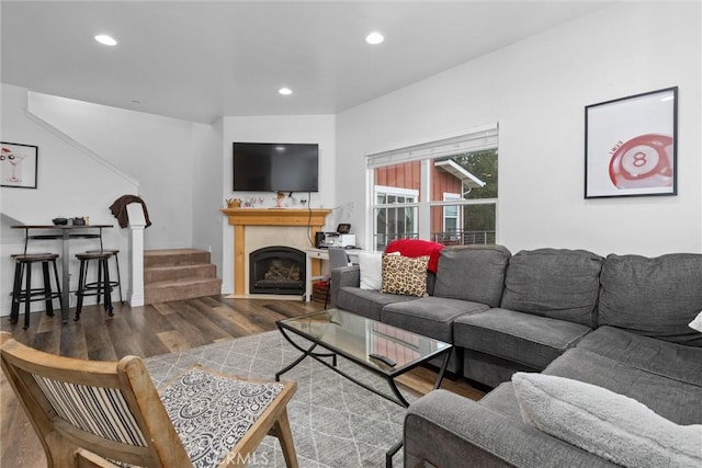 living area featuring a fireplace, stairway, wood finished floors, and recessed lighting