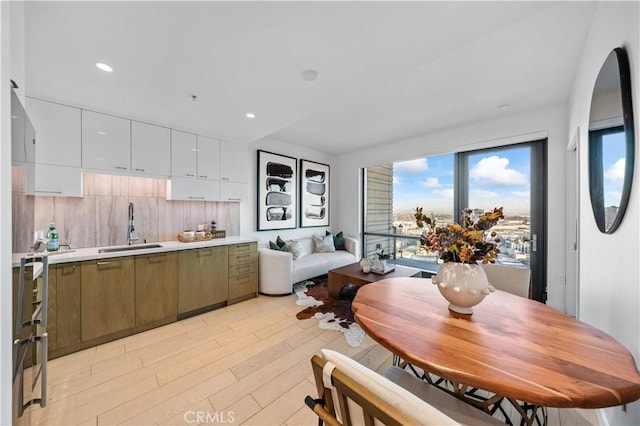 kitchen with light wood finished floors, light countertops, white cabinetry, a sink, and recessed lighting