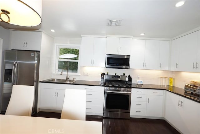 kitchen with appliances with stainless steel finishes, visible vents, a sink, and backsplash