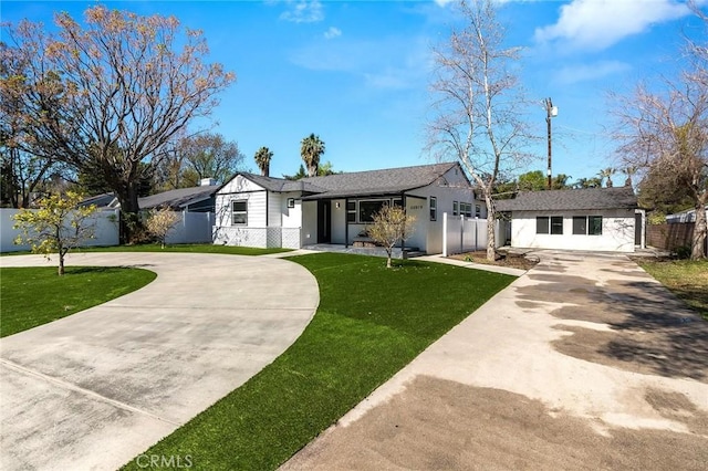 view of front of property with a front yard, concrete driveway, fence, and an outbuilding