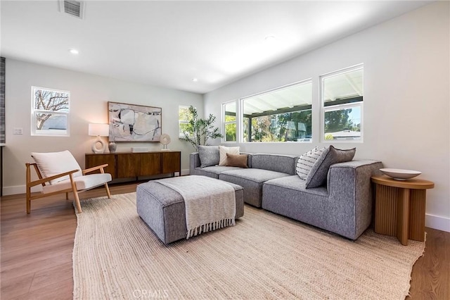 living room with light wood-style flooring, visible vents, baseboards, and recessed lighting