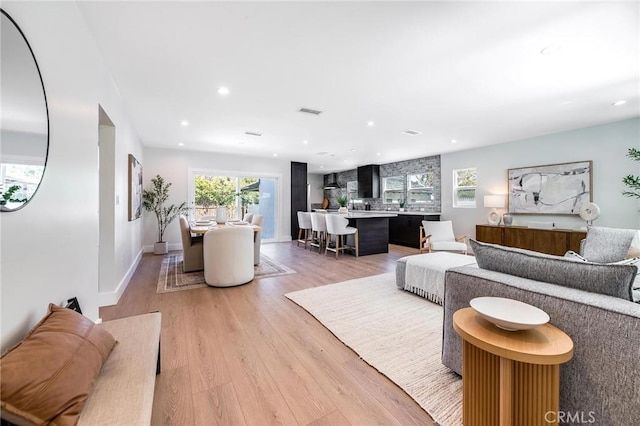 living area with baseboards, recessed lighting, visible vents, and light wood-style floors