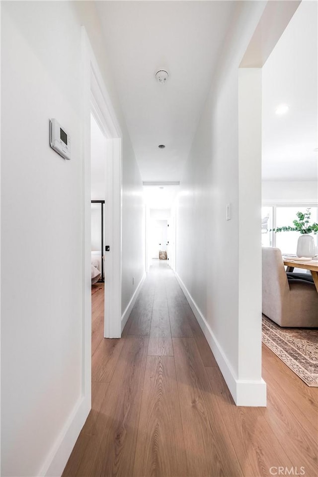 corridor with baseboards and wood finished floors