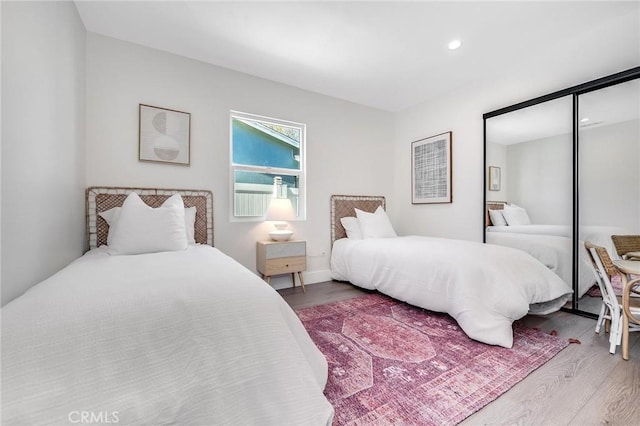 bedroom with recessed lighting, a closet, and wood finished floors