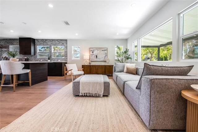 living room with recessed lighting, visible vents, and light wood finished floors