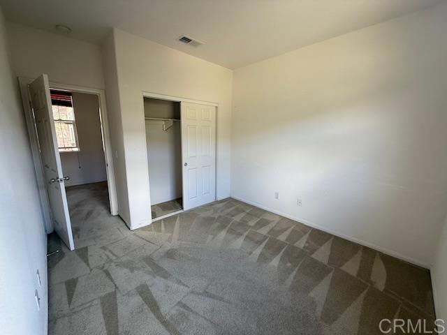 unfurnished bedroom with carpet floors, a closet, and visible vents