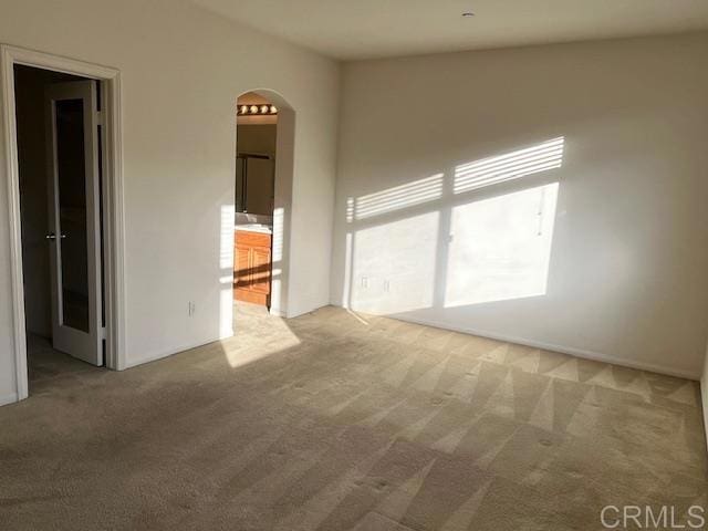 carpeted spare room featuring arched walkways