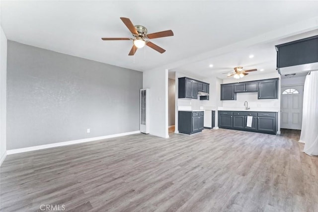 unfurnished living room with a sink, recessed lighting, light wood-style floors, baseboards, and ceiling fan