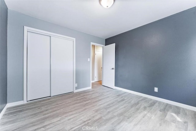 unfurnished bedroom featuring a closet, baseboards, and wood finished floors