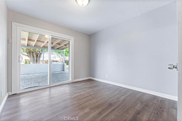 spare room featuring dark wood-type flooring and baseboards
