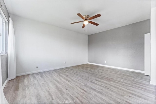 empty room featuring baseboards, wood finished floors, and ceiling fan